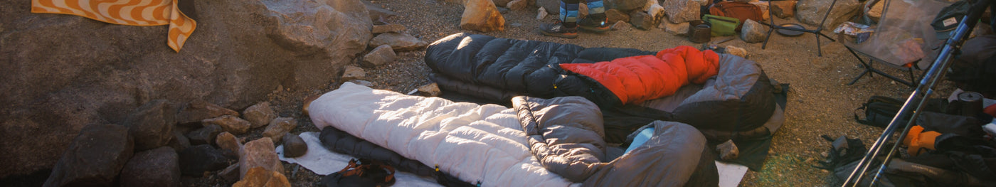 Zenbivy Ultralight Beds with gray, white, and red quilts set up at rocky alpine campsite, showcasing lightweight backpacking sleep systems.