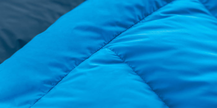 Close-up of soft, blue 50D Polyester Pongee fabric used in Zenbivy sleeping bags, highlighting its smooth, luxurious texture designed for camping comfort.