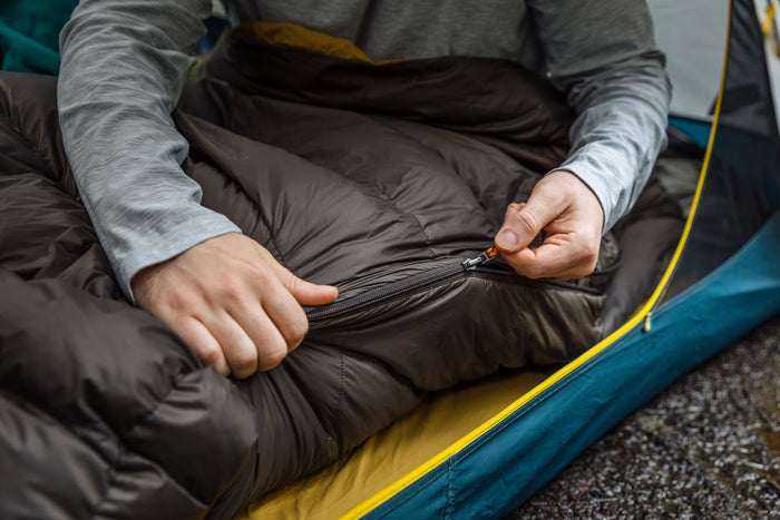 Person zipping up a Zenbivy sleeping bag, highlighting the smooth, easy-to-use zipper system.
