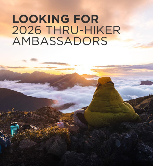 Person wrapped in Zenbivy quilt sitting on a mountain top at sunset with text 'Looking for 2026 Thru-Hiker Ambassadors'.