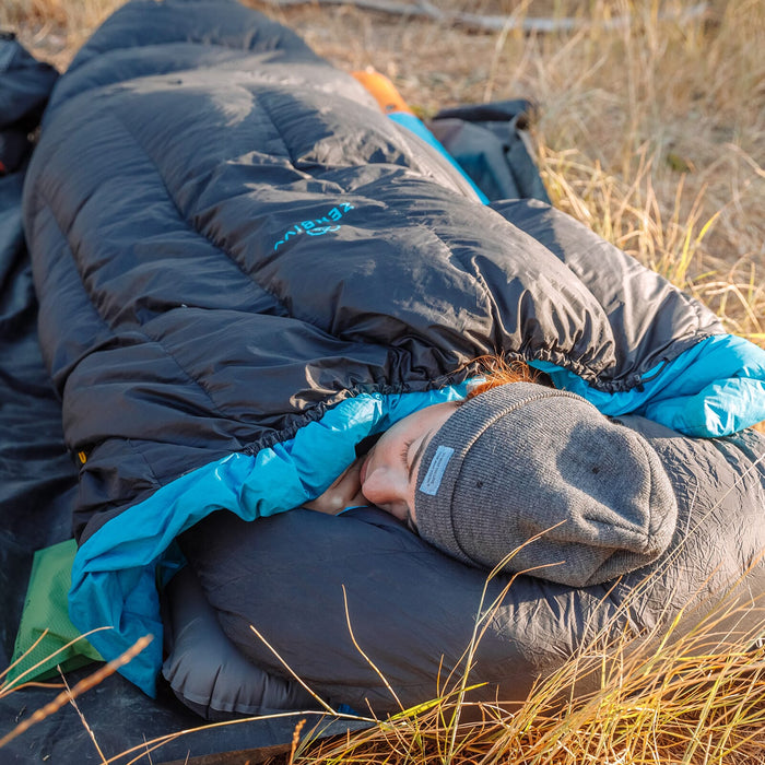 Camper demonstrating the Kylie-curve™. The patent-pending, 3/4 length drawstring along the top of the quilt naturally shapes an internal “dome” of space when cinched, providing ample shoulder room to move and twist freely.